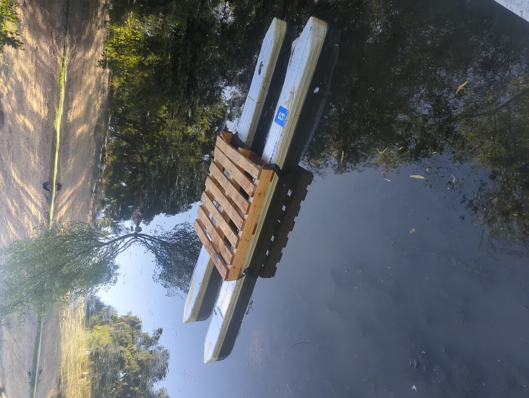 The pontoons, with a wood pallet as their platform, floating in water