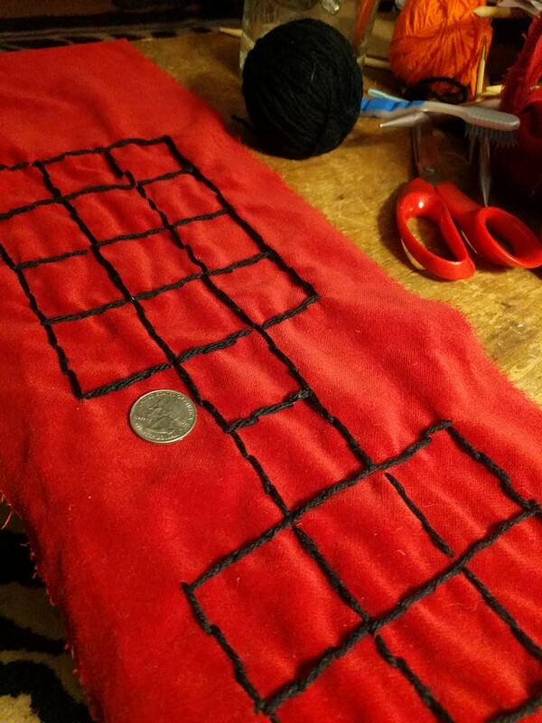 game of ur emulated in black yarn on red fabric