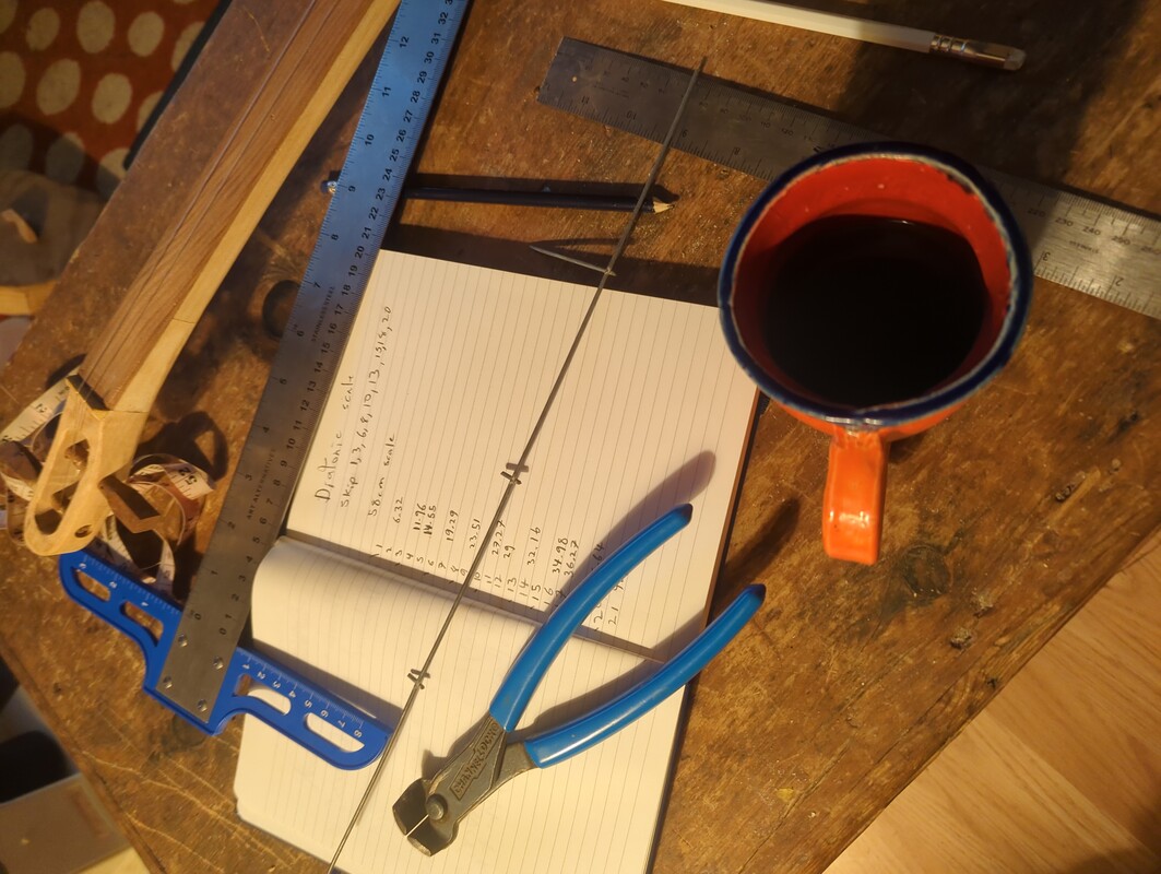 ruler, wire cutter, piece of steel wire, notebook with notes about fret locations