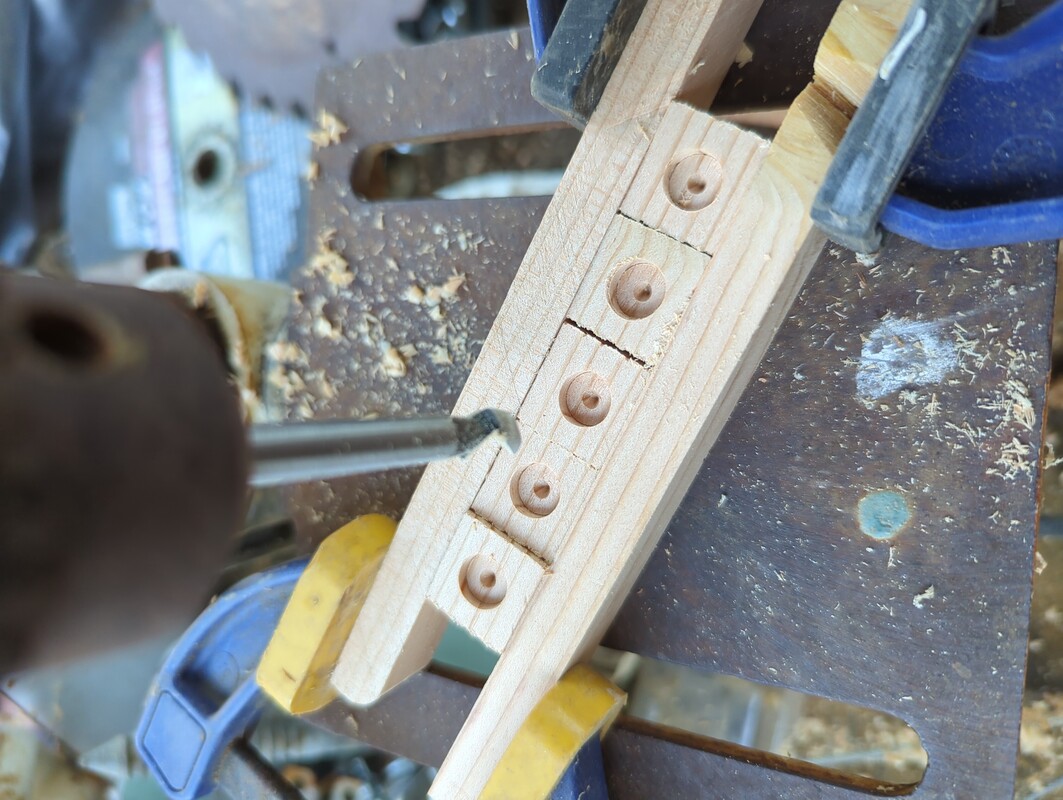 5 Doug Fir cubes clamped together. The cubes are on a drill press bed, with a drill bit hanging above them.