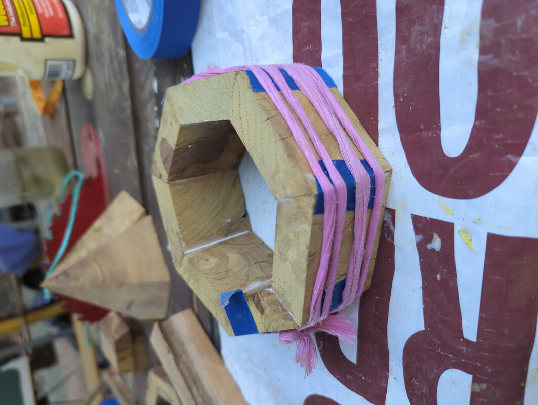 A seven sided ring of wood, clamped together with tape and string