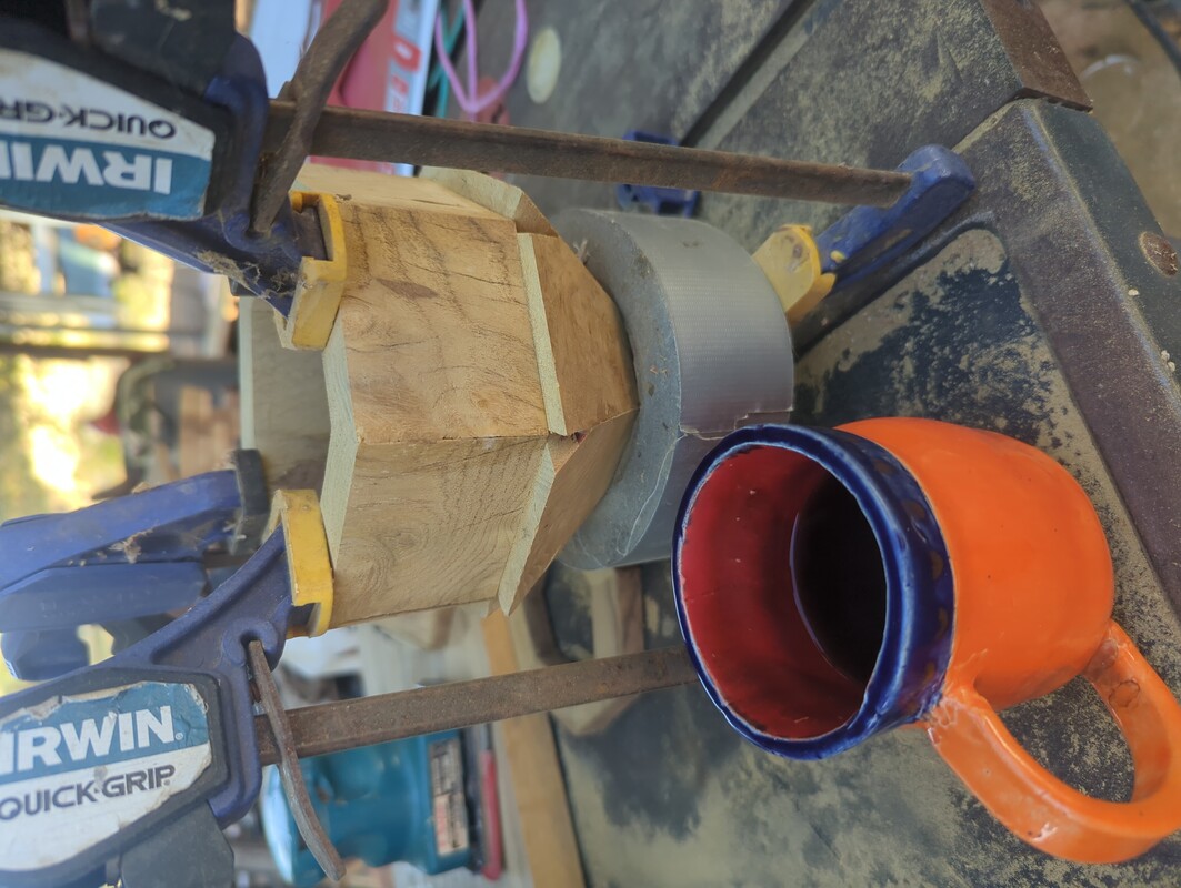 pyramid of wood with the point in a tape roll. There is a ring of wood on the base of the pyramid, and clamps are squeezing the ring onto the pyramid