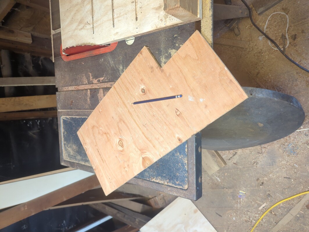 a scrap of thin plywood on a table saw. there is a pencil on the plywood.