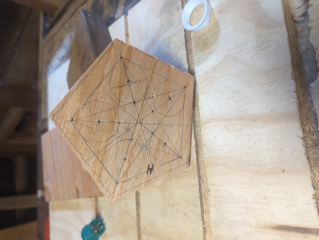 a pentagon of wood, with 5 circle scribed on it in pencil.